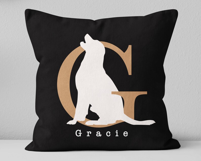 K&ouml;nnte beinhalten: Schwarzes Kissen mit einer wei&szlig;en Silhouette eines Hundes, der in einem braunen Umriss des Buchstabens G sitzt. Der Text "Gracie" ist unter dem Hund gedruckt.