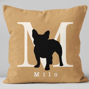 May include: A tan throw pillow with a white letter M and a black silhouette of a French Bulldog. The name Milo is printed below the silhouette.