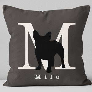May include: A gray throw pillow with a white letter M and a black silhouette of a French Bulldog. The pillow has the name "Milo" printed in white below the silhouette.