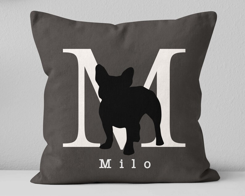 May include: A gray throw pillow with a white letter M and a black silhouette of a French Bulldog. The pillow has the name "Milo" printed in white below the silhouette.