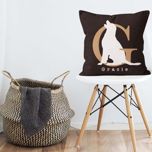 K&ouml;nnte beinhalten: Ein braunes Kissen mit einer wei&szlig;en Silhouette eines Hundes, der vor einem goldenen Buchstaben G sitzt. Das Kissen tr&auml;gt den Namen "Gracie" in wei&szlig; unter dem Hund.
