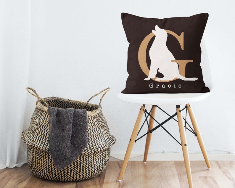 K&ouml;nnte beinhalten: Ein braunes Kissen mit einer wei&szlig;en Silhouette eines Hundes, der vor einem goldenen Buchstaben G sitzt. Das Kissen tr&auml;gt den Namen "Gracie" in wei&szlig; unter dem Hund.
