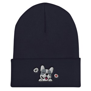 Puede incluir: Un gorro de punto azul marino con un perro de dibujos animados bordado en blanco y gris que lleva un coraz&oacute;n rojo. El perro dice "Hola" en un globo de di&aacute;logo.