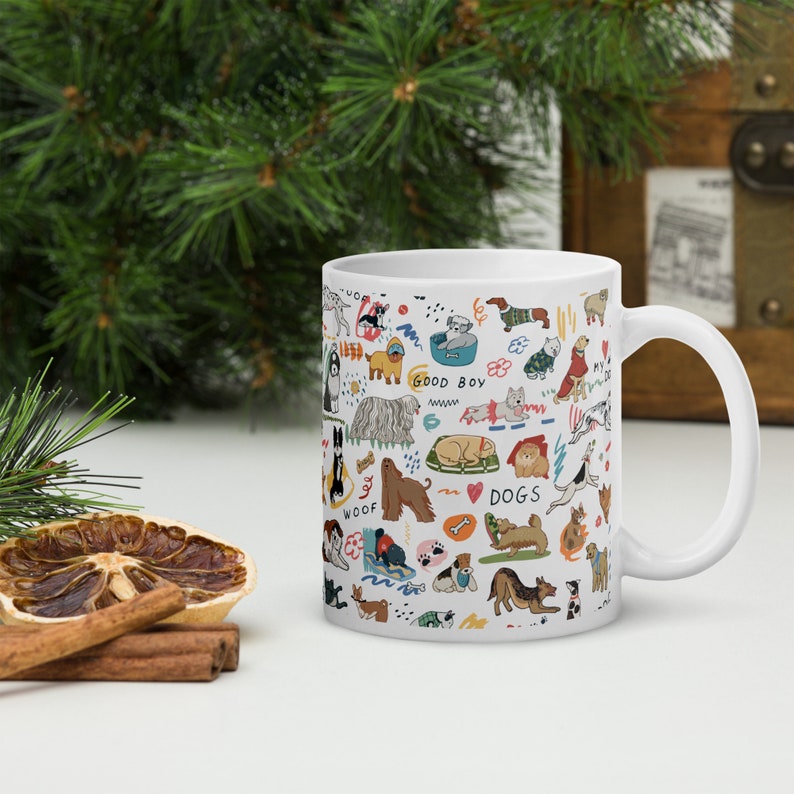May include: White ceramic mug with a colorful pattern of dogs, bones, and paw prints. The text "Woof", "Good Boy", and "Dogs" is included in the design.