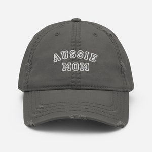 May include: A gray distressed baseball cap with white embroidered text that reads "Aussie Mom".