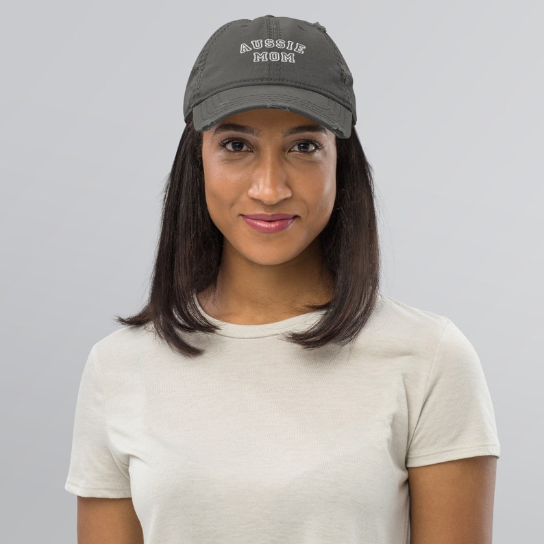 May include: A gray distressed baseball cap with white embroidered text that reads "Aussie Mom".
