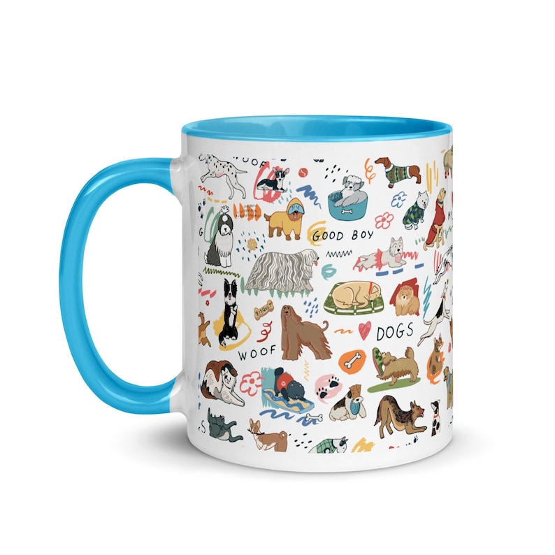 Op de afbeelding: Een witte keramische mok met een blauwe rand. De mok heeft een kleurrijke illustratie van verschillende hondenrassen, waaronder een dalmati&euml;r, een mops, een golden retriever en een corgi. De illustratie bevat ook de woorden "Woof", "Good Boy" en "Dogs".