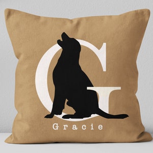 K&ouml;nnte beinhalten: Ein braunes Kissen mit einem wei&szlig;en Buchstaben G und einer schwarzen Silhouette eines Hundes, der im Buchstaben sitzt. Der Name "Gracie" ist unter dem Buchstaben gedruckt.