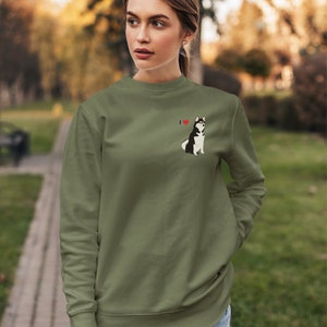 Może przedstawiać: Zielona bluza z małym haftowanym obrazkiem husky i tekstem "I &hearts;" na lewej piersi.