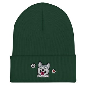 K&ouml;nnte beinhalten: Eine dunkelgr&uuml;ne M&uuml;tze mit einem gestickten Husky-Hund in Wei&szlig; und Grau, der die Zunge herausstreckt. Der Hund sagt "Hallo" in einer Sprechblase und es gibt ein rotes Herz in einer anderen Sprechblase.