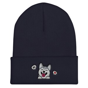 K&ouml;nnte beinhalten: Eine marineblaue M&uuml;tze mit einem gestickten Husky-Hundegesicht in Wei&szlig; und Grau, einem roten Herzen und dem Wort "HI" in einer Sprechblase.