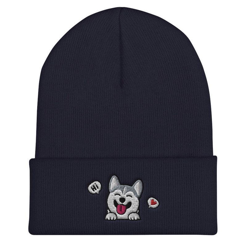 K&ouml;nnte beinhalten: Eine marineblaue M&uuml;tze mit einem gestickten Husky-Hundegesicht in Wei&szlig; und Grau, einem roten Herzen und dem Wort "HI" in einer Sprechblase.
