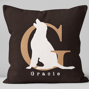 K&ouml;nnte beinhalten: Ein braunes Kissen mit einer wei&szlig;en Silhouette eines Hundes, der in einem beigen Buchstaben G sitzt. Der Text "Gracie" ist unter dem Hund gedruckt.