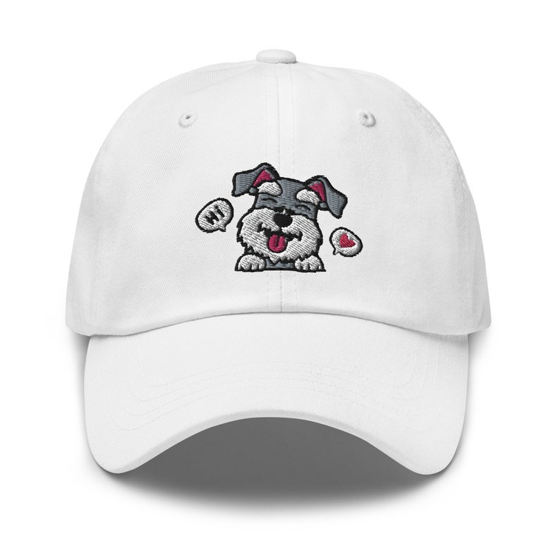 K&ouml;nnte beinhalten: Wei&szlig;e Baseballkappe mit einem gestickten Cartoon-Bild eines grau-wei&szlig;en Zwergschnauzers mit herausgestreckter Zunge. Der Hund sagt "Hallo" in einer Sprechblase und hat ein rotes Herz in einer anderen Sprechblase.
