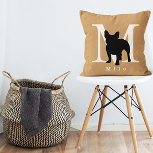 May include: A tan throw pillow with a white letter M and a black silhouette of a French Bulldog. The pillow has the name "Milo" printed on it.