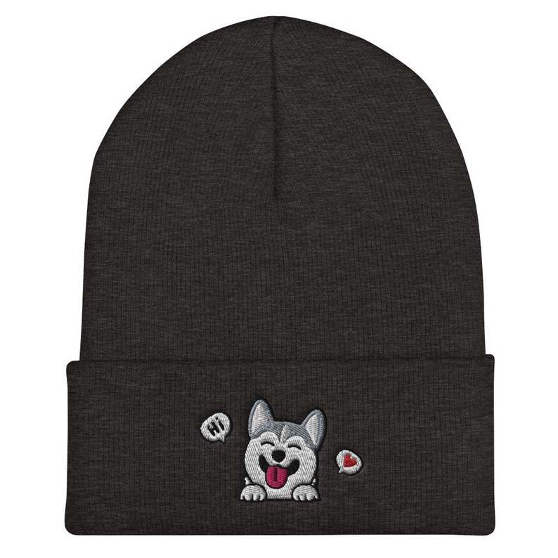 K&ouml;nnte beinhalten: Eine dunkelgraue M&uuml;tze mit einem wei&szlig;en gestickten Husky-Hund mit herausgestreckter rosa Zunge. Der Hund sagt "Hallo" in einer Sprechblase und hat ein rotes Herz in einer anderen Sprechblase.