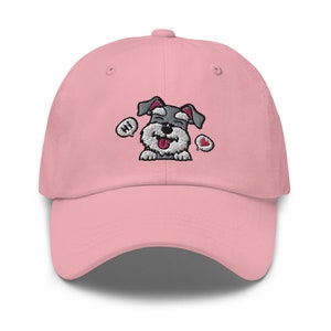 K&ouml;nnte beinhalten: Eine rosafarbene Baseballkappe mit einem gestickten Cartoon-Bild eines grau-wei&szlig;en Zwergschnauzers mit herausgestreckter Zunge. Der Hund tr&auml;gt ein rotes Herz und eine Sprechblase mit der Aufschrift "Hallo".