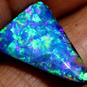 Peut inclure: Une pierre d'opale triangulaire avec un affichage de couleurs vives. La pierre présente un mélange de teintes bleues, vertes et violettes, créant un effet chatoyant et irisé. L'opale est tenue dans une main, mettant en valeur sa beauté naturelle.