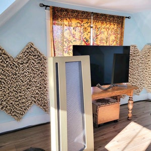 May include: A home theater setup with two large beige speakers, a flat screen television, and acoustic panels on the walls. The television is mounted on a wooden shelf with a wooden box underneath.