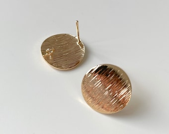 May include: A pair of gold-toned round stud earrings with a textured surface.