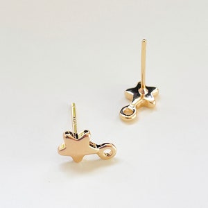 May include: A pair of gold-tone star-shaped earring posts with a small loop on the side.