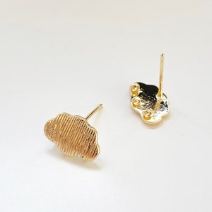 May include: A pair of gold-tone cloud shaped earring studs. The earrings have a textured surface and are designed to be worn as a pair.