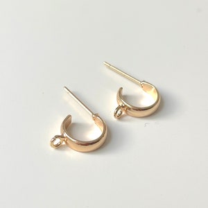 May include: A pair of gold-toned hoop earrings with a small jump ring on each hoop. The earrings are designed for pierced ears.