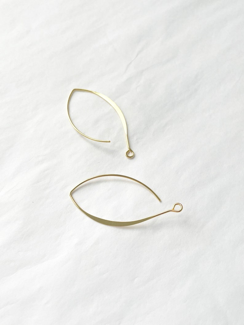 May include: Two gold leaf-shaped earring hoops with a small loop at the end of each hoop.