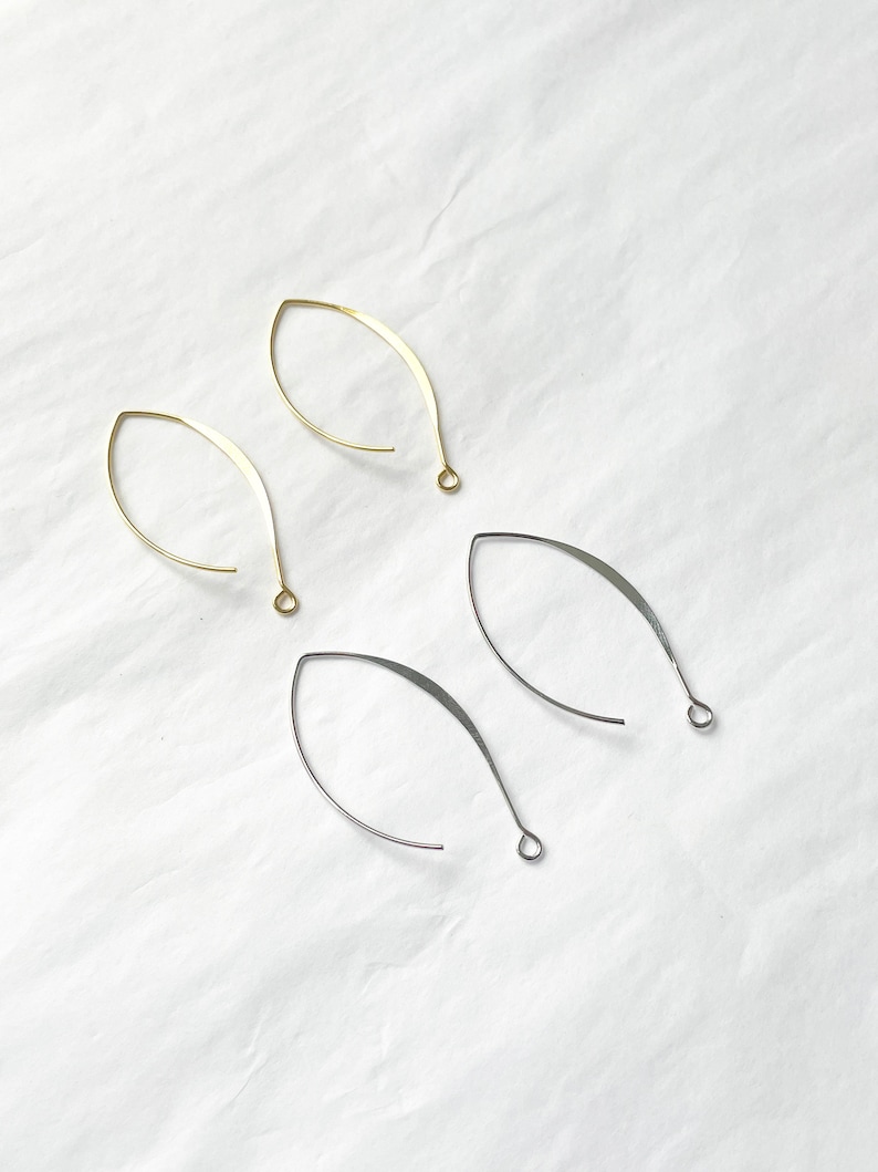 May include: Four earring findings, two gold and two silver, in the shape of a teardrop with a loop at the top.
