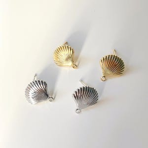 May include: Four seashell shaped earring findings, two gold and two silver, with a loop at the bottom for attaching a dangle charm.