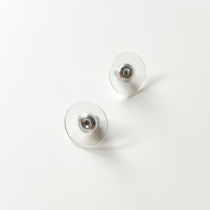 K&ouml;nnte beinhalten: Ein Paar durchsichtige Ohrstecker aus Kunststoff mit silbernen Metallstiften.