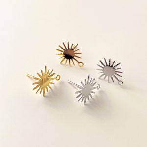 May include: Three sunburst earring settings in gold, silver, and rose gold. Each setting has a round, flat centre with a small loop on the side for attaching a bead or charm.
