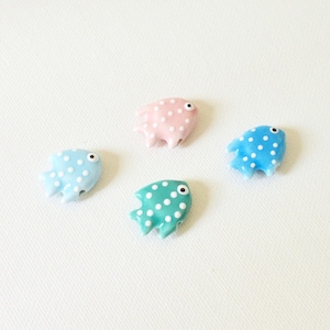 May include: Four small fish-shaped beads in light blue, pink, teal, and bright blue. Each bead features a smooth, glossy finish with a pattern of small white polka dots and a single black and white eye detail, designed for jewelry making projects.
