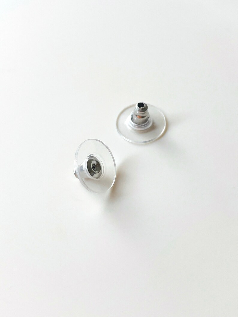 K&ouml;nnte beinhalten: Zwei transparente Ohrstecker aus Kunststoff mit einem silbernen Metallstift.