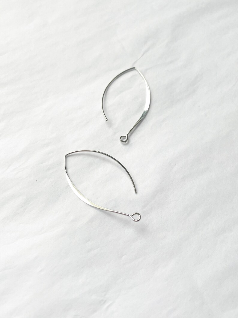 May include: Two silver earring hoops with a slightly curved shape.