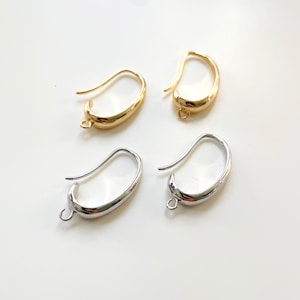 May include: Two pairs of earring hooks, one pair is gold and the other is silver. The hooks are curved and have a small loop at the end.