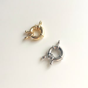 Puede incluir: Dos cierres metálicos para la elaboración de joyas. Uno es dorado y el otro plateado.