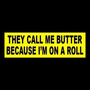May include: Yellow rectangular sign with black text that reads "They call me butter because I'm on a roll."