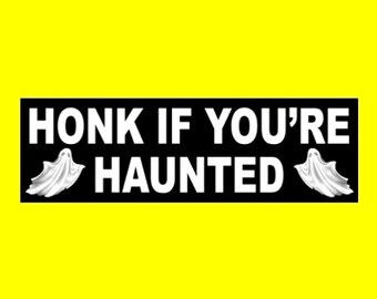 May include: Black and white bumper sticker with the text "HONK IF YOU'RE HAUNTED" and two white ghost silhouettes on either side.