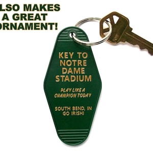 May include: Green key chain shaped like a hotel key with gold lettering that reads "Key to Notre Dame Stadium, Play like a Champion Today, South Bend, IN, Go Irish!"