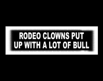 May include: White rectangular sign with black text that reads "Rodeo clowns put up with a lot of bull."