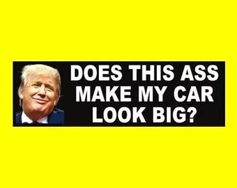 May include: A black and white bumper sticker with a photo of a man and the text "DOES THIS ASS MAKE MY CAR LOOK BIG?"