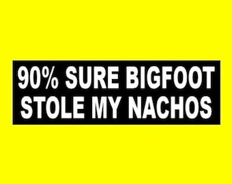 May include: Black and white bumper sticker with the text "90% SURE BIGFOOT STOLE MY NACHOS".