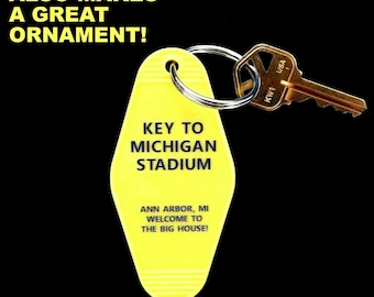 May include: Yellow plastic key chain shaped like a hotel key with the text "KEY TO MICHIGAN STADIUM" and "ANN ARBOR, MI WELCOME TO THE BIG HOUSE!" A gold key is attached to the key chain.