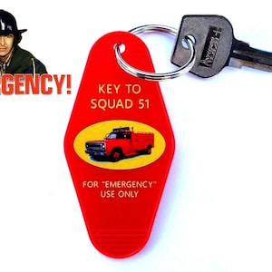 May include: Red key tag with the text "KEY TO SQUAD 51" and a red truck graphic. The tag also has the text "FOR 'EMERGENCY' USE ONLY". A key is attached to the tag. The image also includes the word "EMERGENCY!" and two men in firefighter hats.
