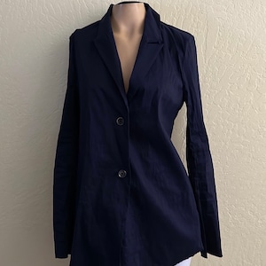 May include: A navy blue blazer with a notched lapel and two-button closure. The long-sleeved jacket is displayed on a mannequin and has a slightly flared hemline. The blazer is made of a smooth fabric.