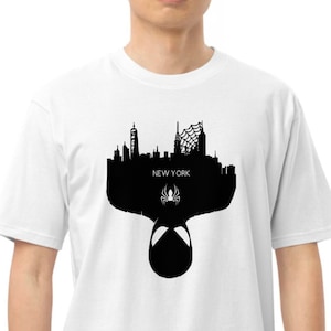 May include: White t-shirt featuring a black silhouette of the New York City skyline, a spider symbol, and the text "NEW YORK". The design includes the Spider-Man mask.