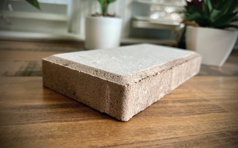 May include: A light brown rectangular brick with a smooth, light gray top surface. The brick has a slightly rough texture on the sides.