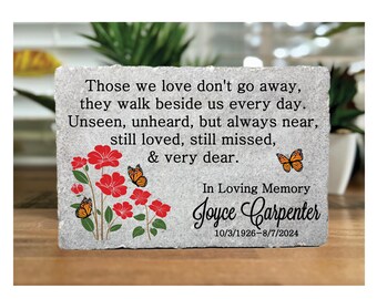 May include: A rectangular memorial stone with the inscription "Those we love don't go away..." and "In Loving Memory Joyce Carpenter 10/3/1926-8/7/2024." Features red flowers, green leaves, and orange butterflies. The stone has a textured, gray surface.