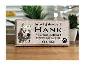 May include: A white concrete memorial brick with a black and white drawing of a dog and the text "In Loving Memory of HANK A Brave and Loyal Friend Forever Loved & Missed 2008-2022"